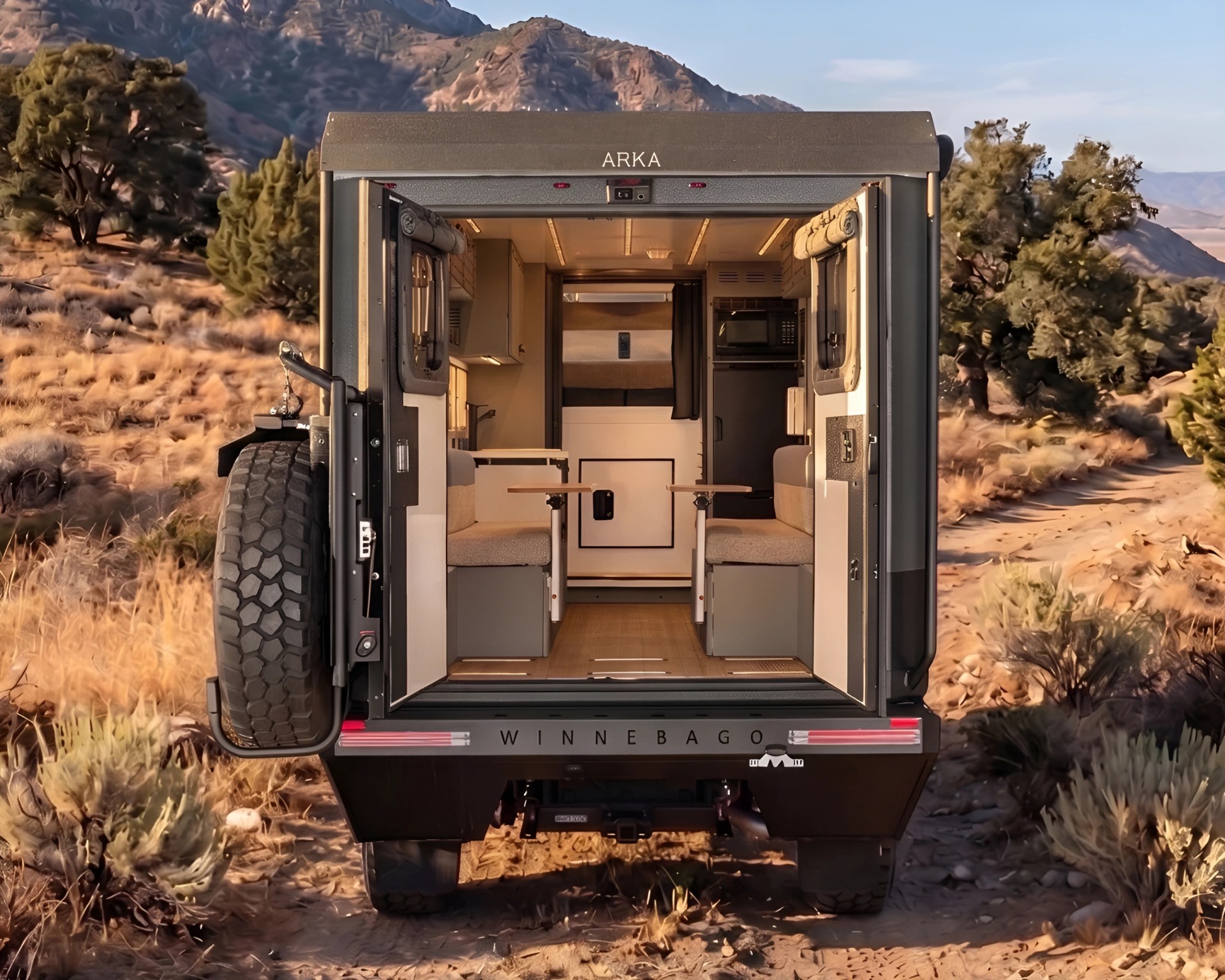 Rear view of a Winnebago ARKA camper with open doors showing interior seating and tables in a desert landscape.