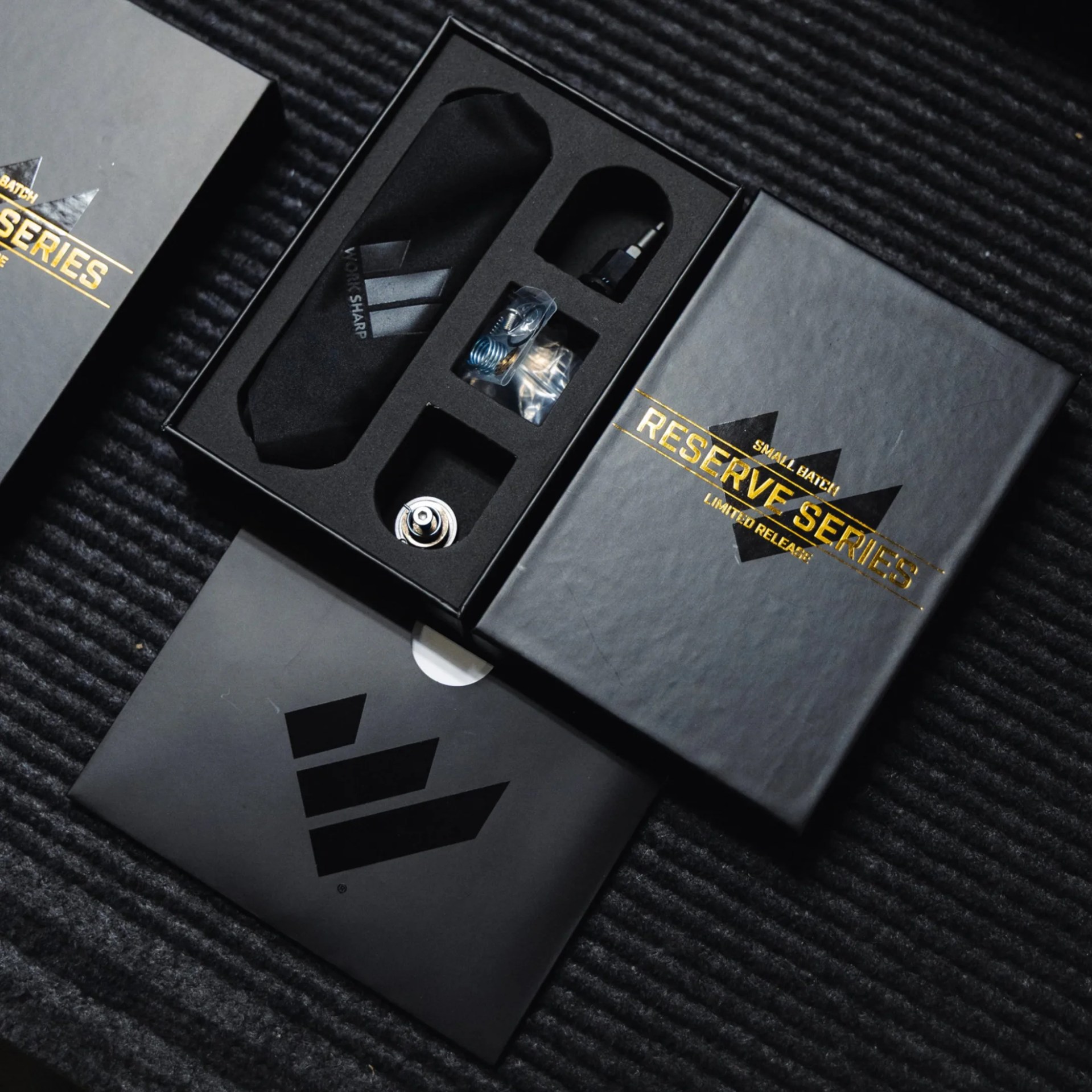 Black foam-lined box with small mechanical parts and a black cloth pouch, labeled "Reserve Series.