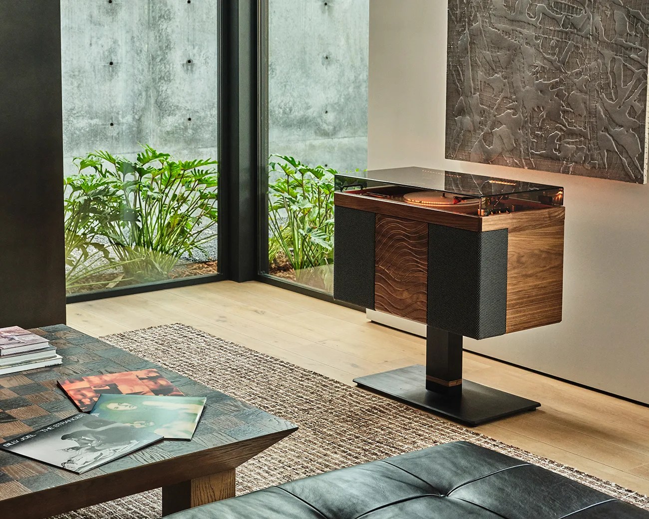 Wooden turntable with black speaker panels on a black metal stand in a modern living room corner.