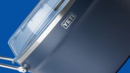 Close-up of a blue YETI cooler with a clear lid and silver metal handle against a blue background.