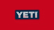 YETI logo with white letters decorated with stars and stripes on a blue rectangular background and red surrounding.