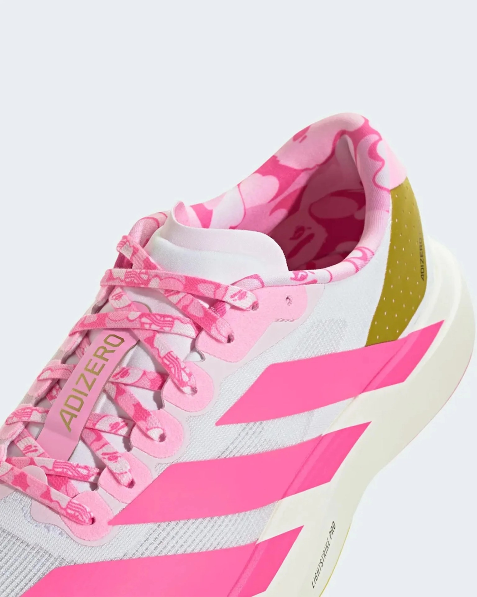 Close-up of a white and pink Adidas Adizero sneaker with floral-patterned pink laces and inner lining, and olive green heel detail.