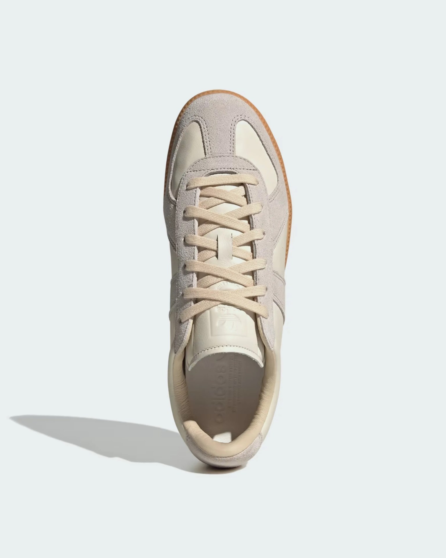 Beige and off-white suede and leather sneaker with cream laces and gum sole viewed from above.