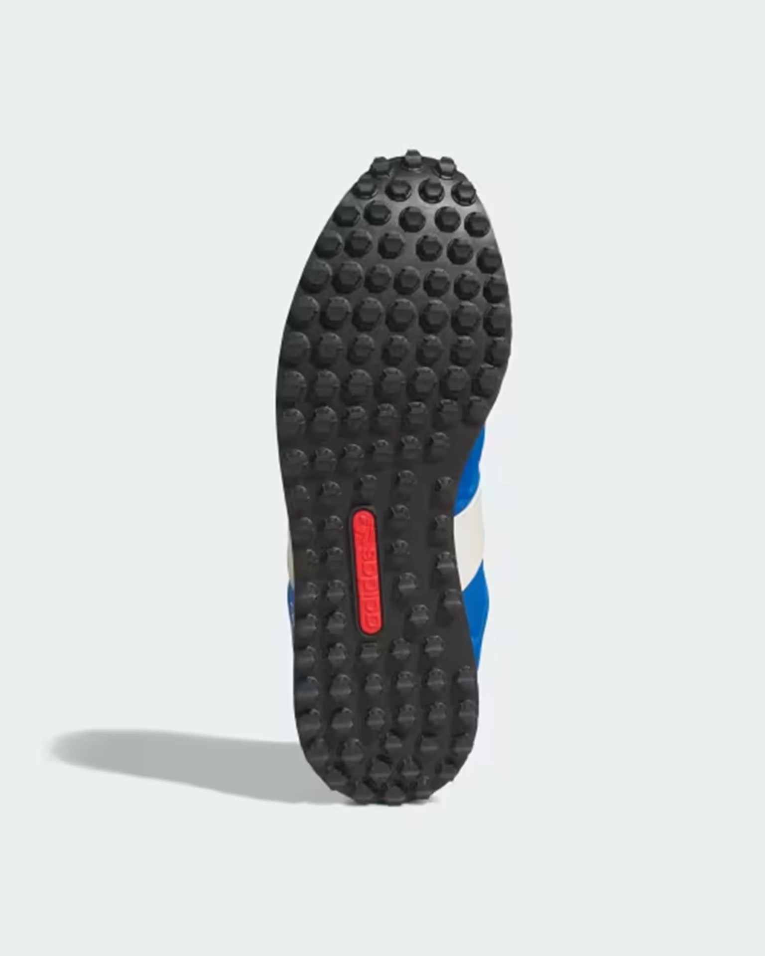 Black rubber shoe sole with circular studs and a red Adidas logo strip in the center.