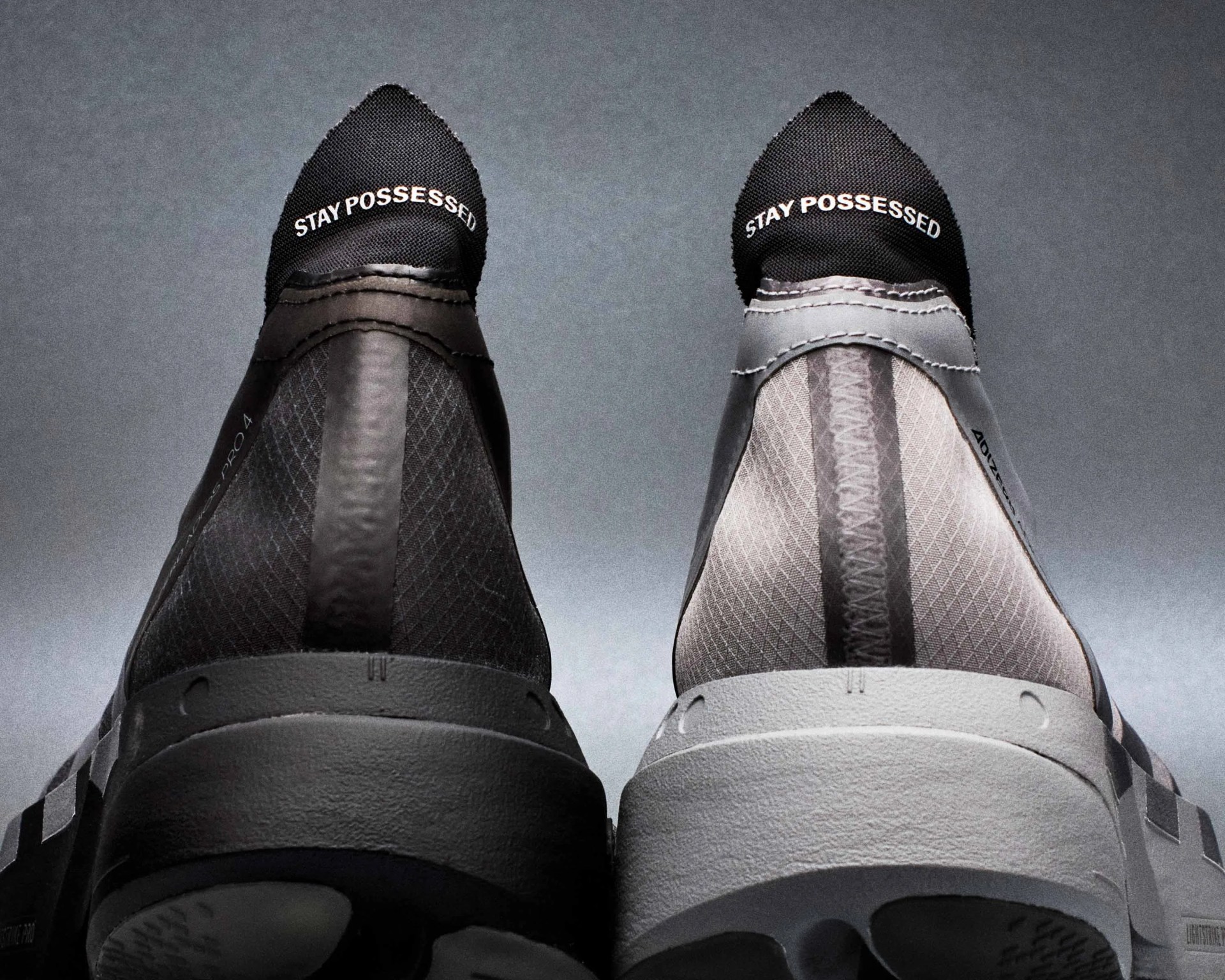 Pair of black and white sneakers with "STAY POSSESSED" text on the heel tabs against a gray background.