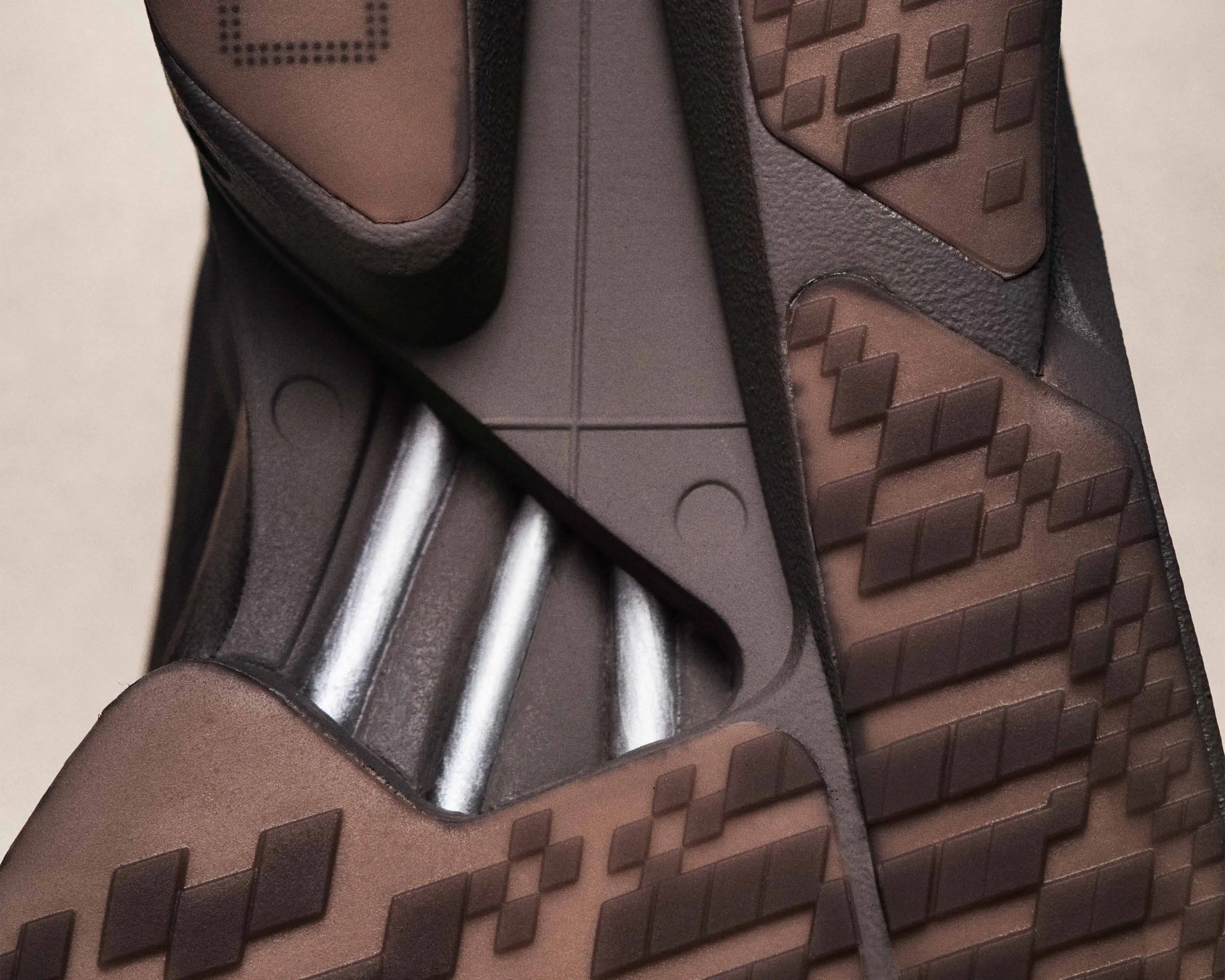 Close-up of a brown and black shoe sole with textured geometric patterns and metallic silver accents.