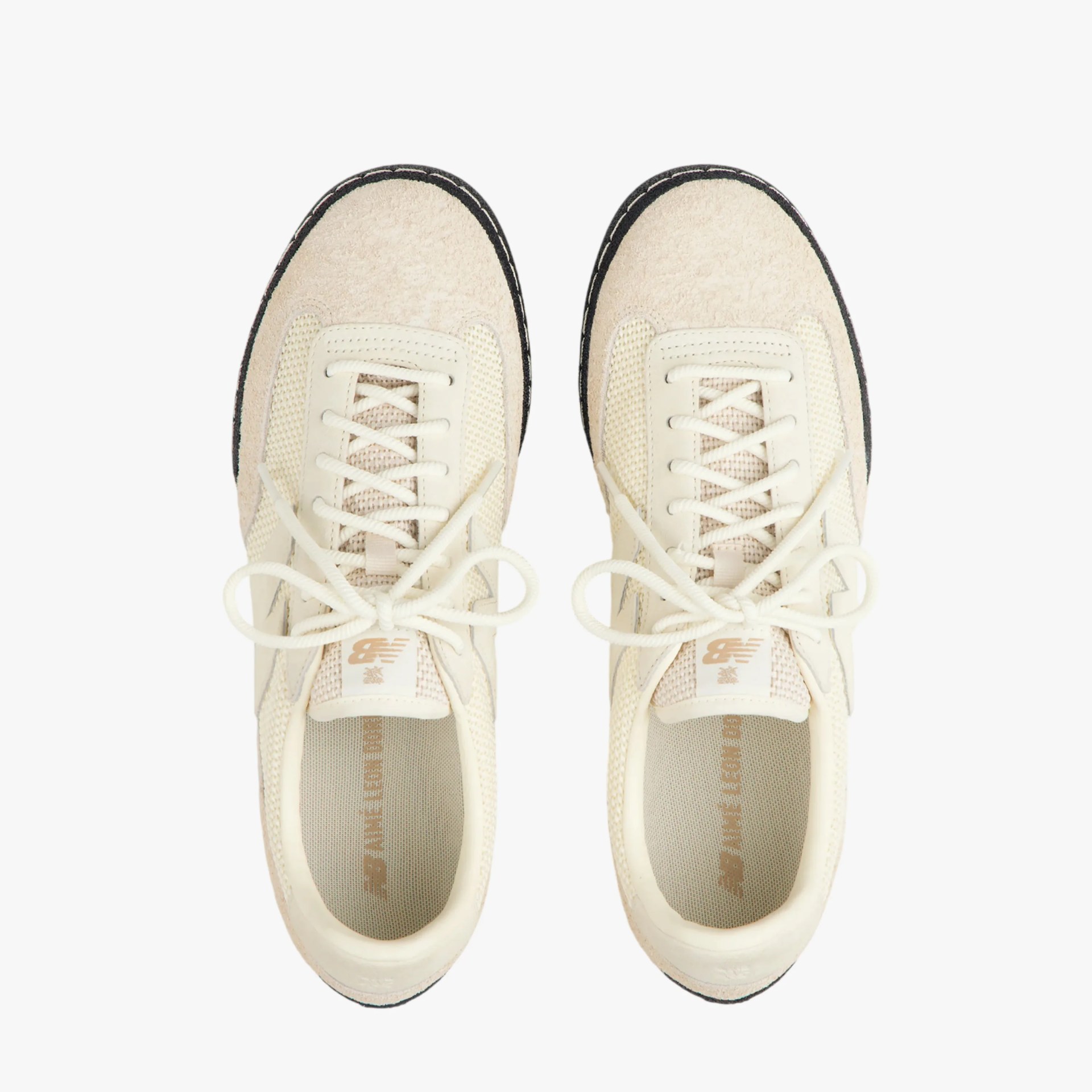 Pair of cream-colored New Balance sneakers with textured toe caps and white laces viewed from above.