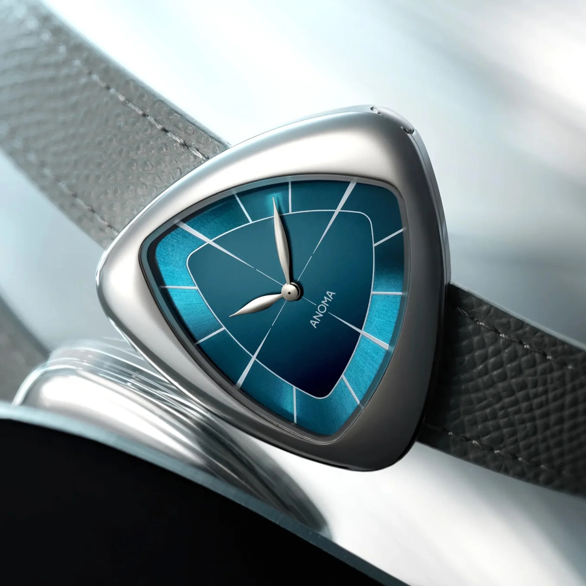 Close-up of a triangular silver watch case with a blue dial and a textured gray leather strap.