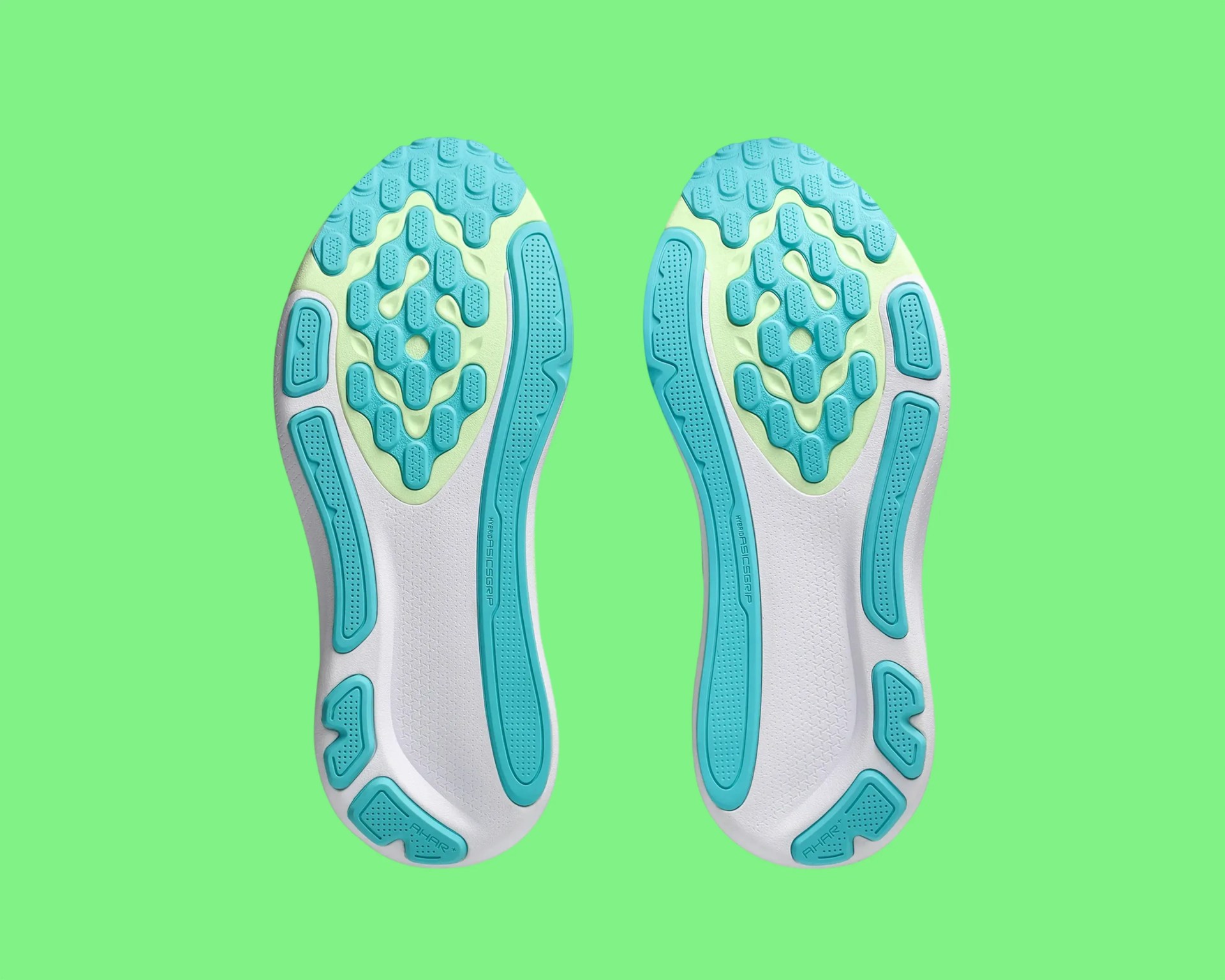 White and turquoise shoe soles with textured grip patterns on a green background.