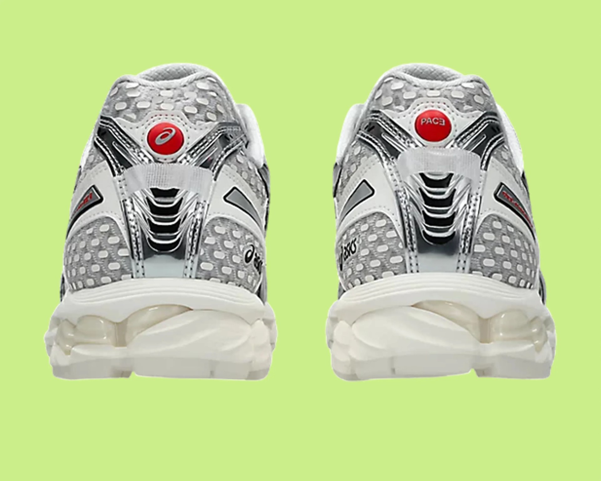 Pair of white and gray Asics running shoes with red circular logos on the heels against a light green background.