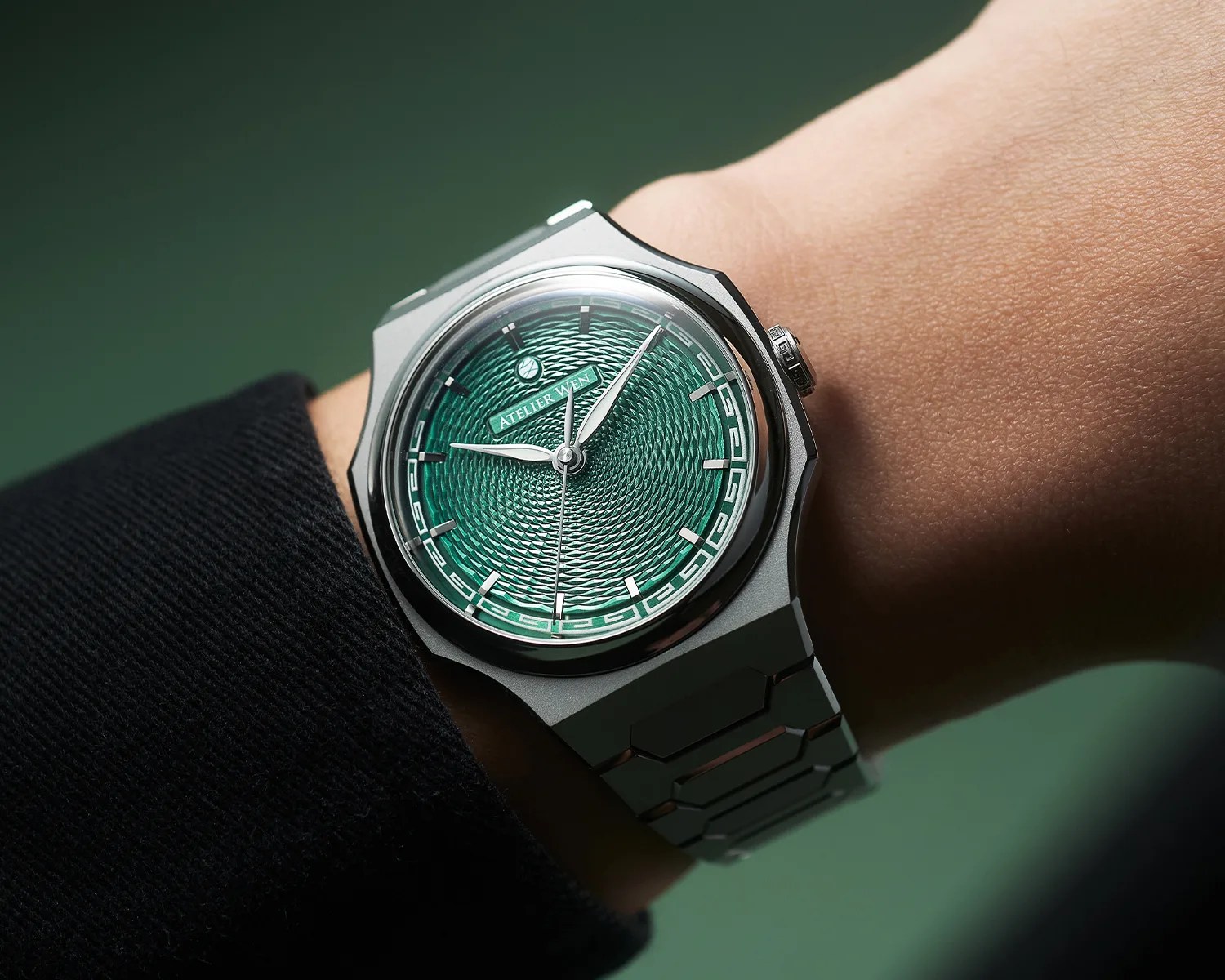 Silver metal wristwatch with a textured green dial and "ATELIER WEN" logo worn on a wrist.
