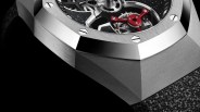 Close-up of a luxury watch with a brushed metal octagonal bezel, visible gears, red mechanical component, and textured black strap.