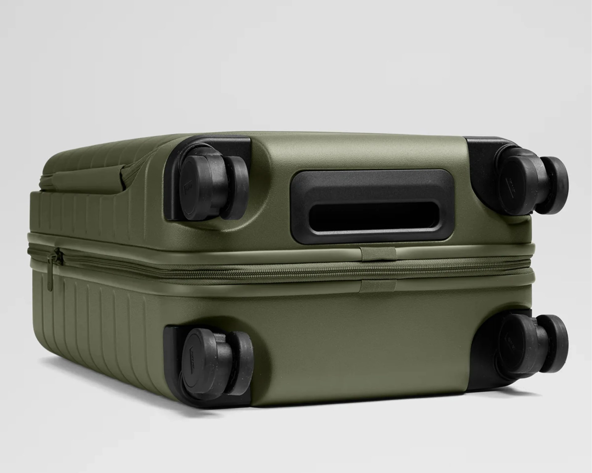 Olive green hard-shell suitcase lying on its side showing four black spinner wheels and a recessed handle.