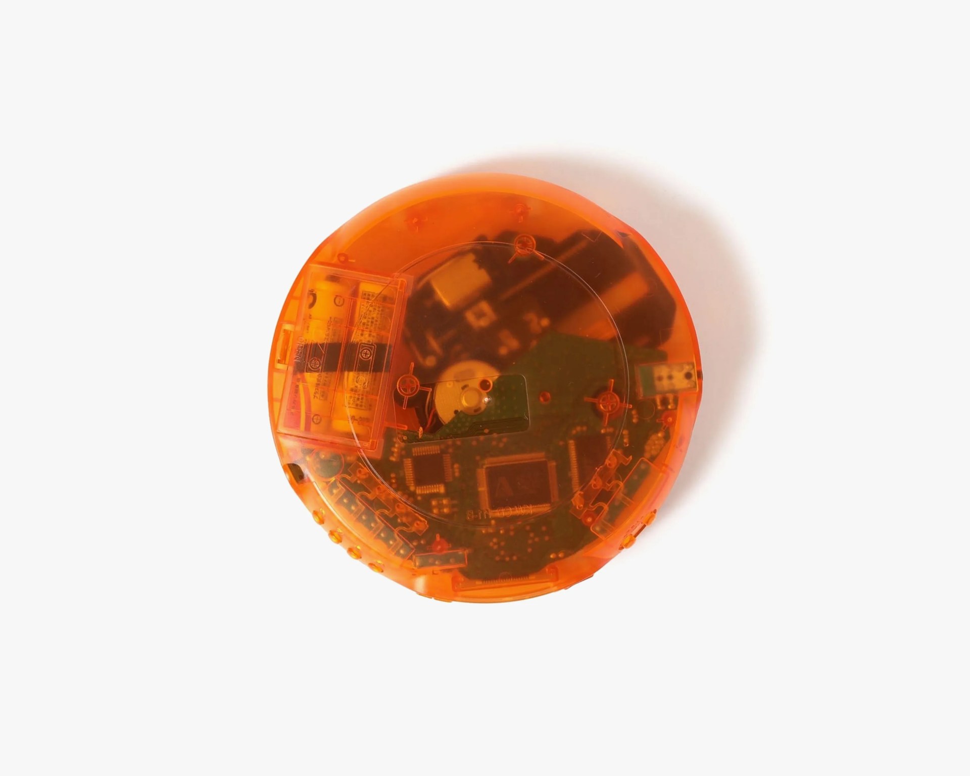 Orange translucent circular electronic device showing internal circuit board and battery compartment.