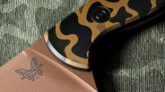 Close-up of a Benchmade knife blade with a butterfly logo and a camo-patterned handle.
