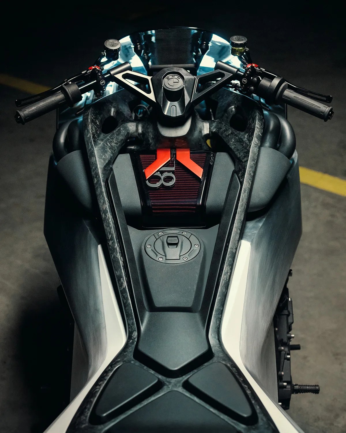 Top view of a black and gray BMW motorcycle fuel tank and handlebars with a red air filter visible.