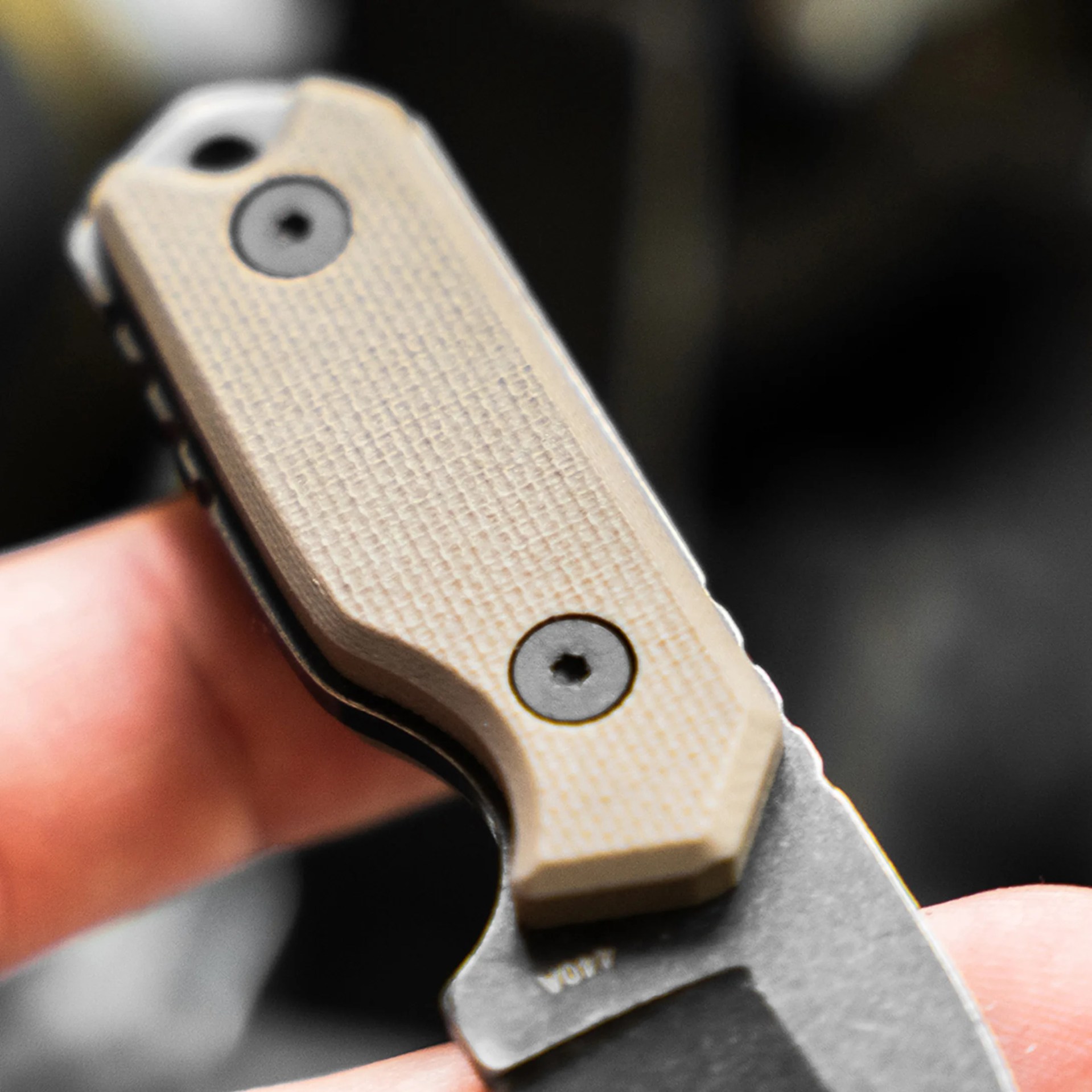 Close-up of a beige textured knife handle with black screws and a partially visible blade.