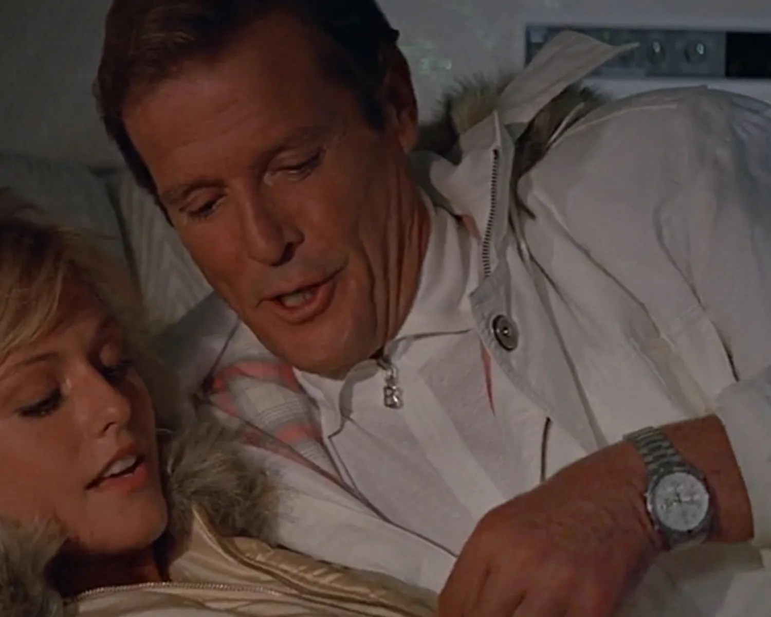 Close-up of two people wearing white jackets, one with a silver wristwatch, looking down together.