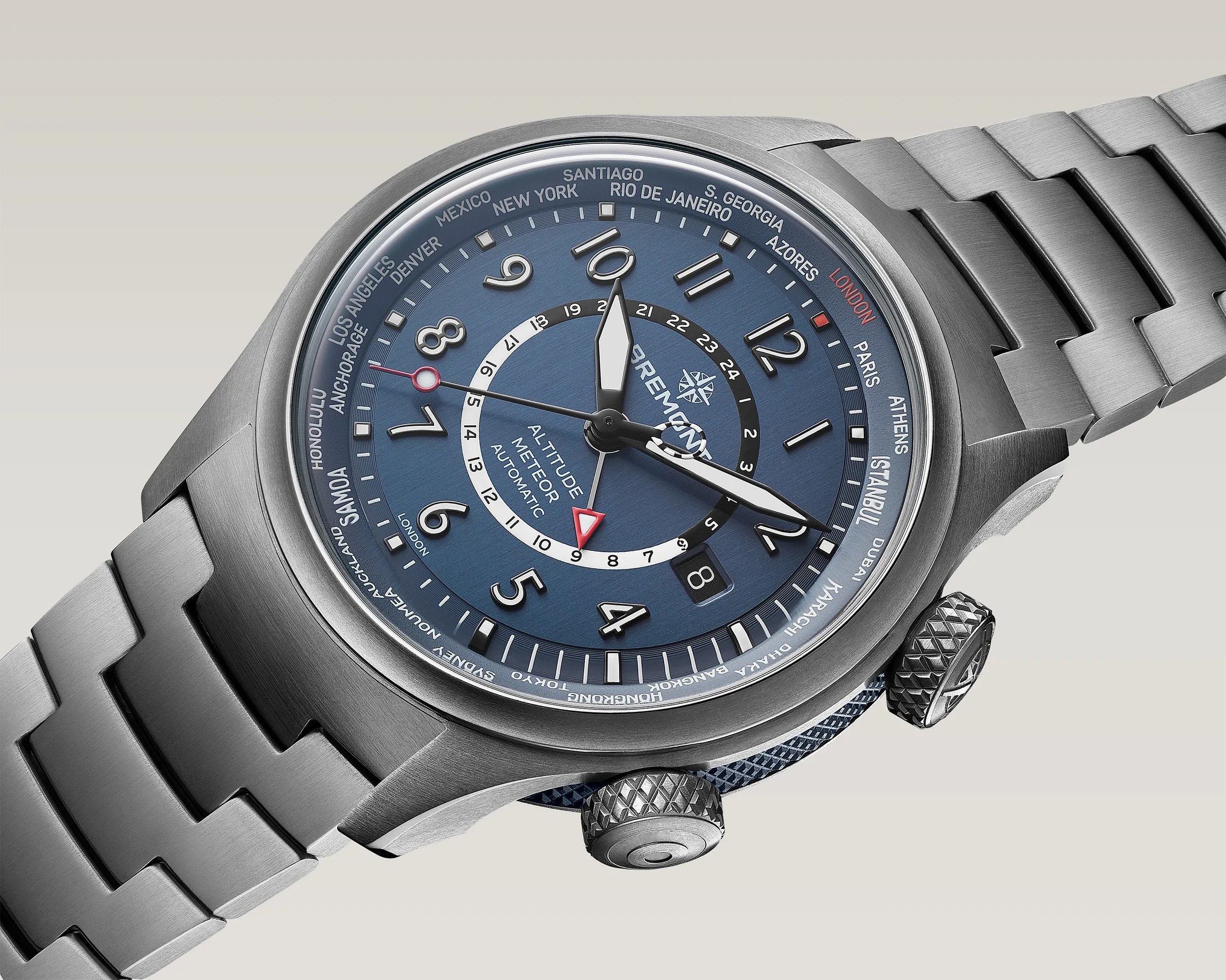 Brushed stainless steel wristwatch with blue dial, world cities on bezel, and metal link bracelet.