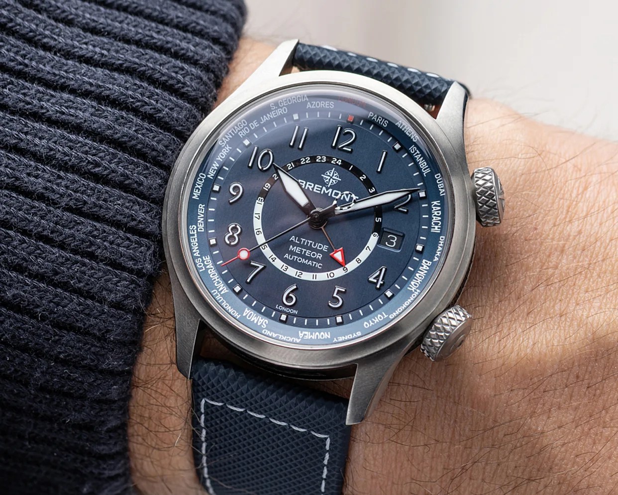 Blue Bremont Altitude Meteor automatic watch with city names on bezel and textured blue strap worn on wrist.