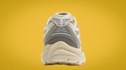 Rear view of a beige and gray Brooks running shoe against a yellow background.