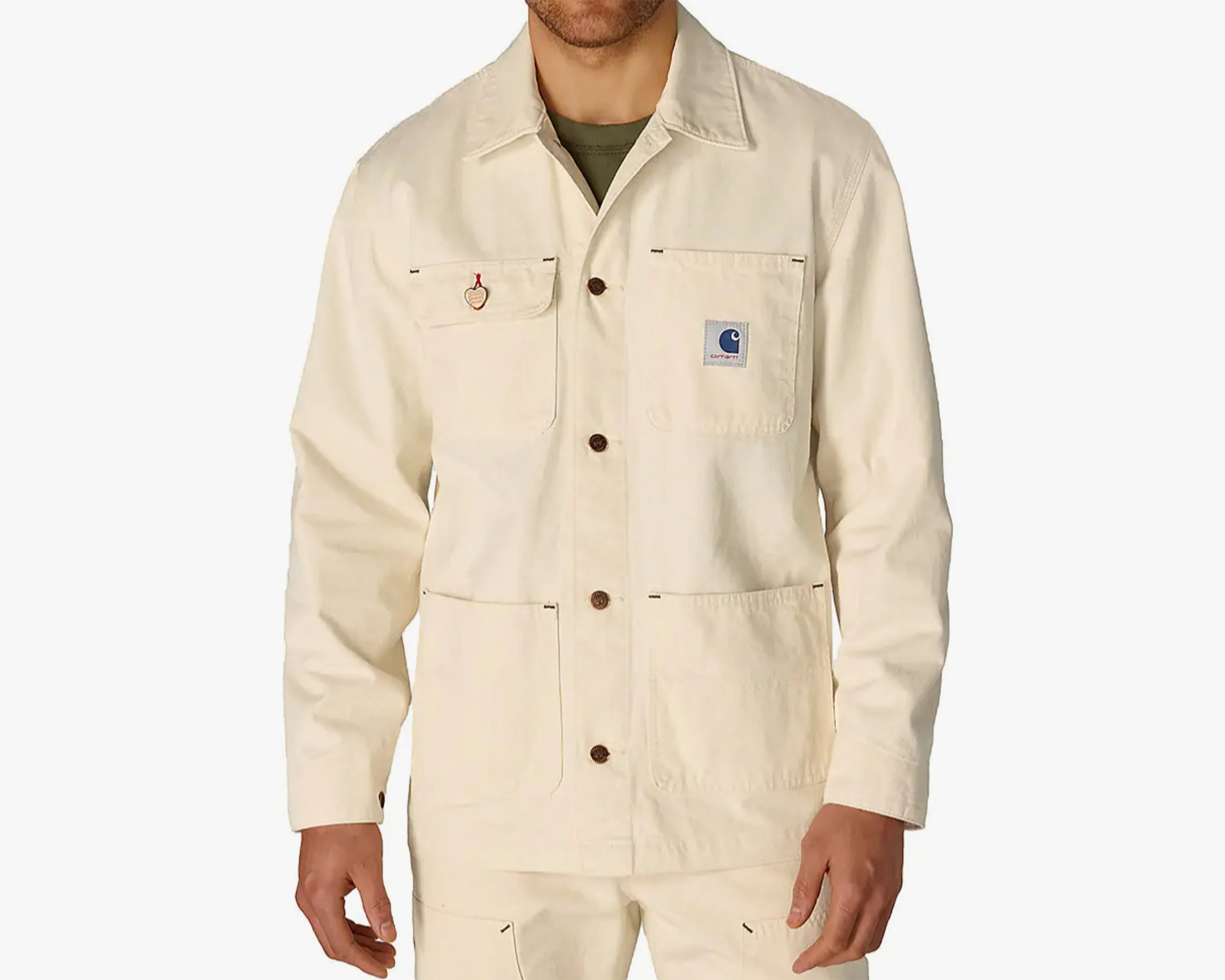 Off-white Carhartt jacket with button closure and four front pockets, worn over an olive green shirt.