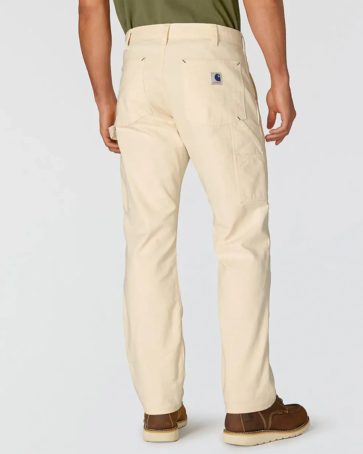 Beige Carhartt work pants with back pockets and a logo patch, worn with brown work boots.