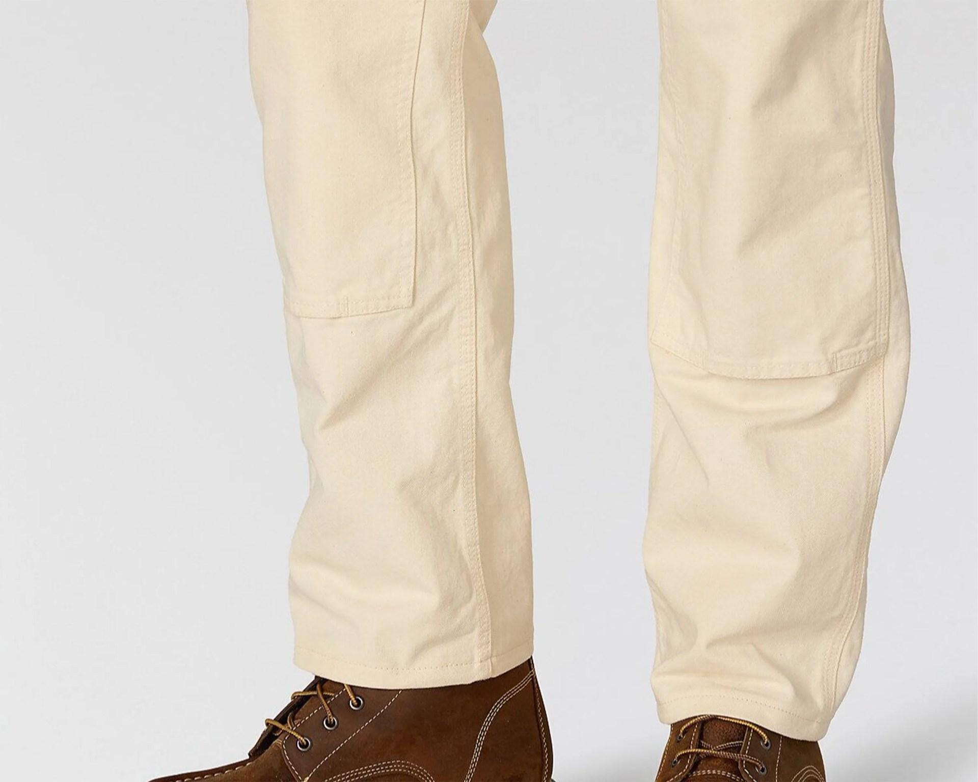 Beige pants with reinforced knee patches worn with brown leather lace-up boots.