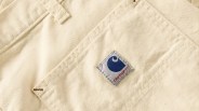 Close-up of beige fabric with a stitched Carhartt logo patch in blue and red.