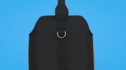 Black fabric strap with a metal D-ring on a blue background.