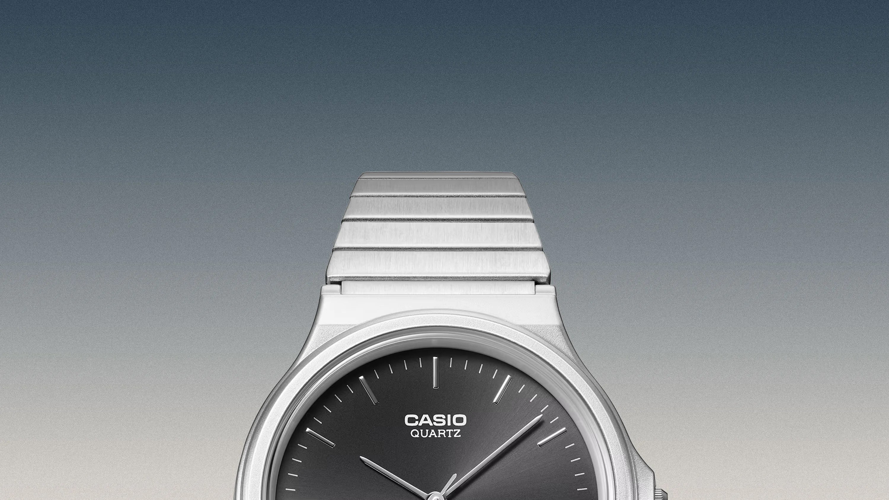 Silver Casio quartz watch with black dial and metal link band against gradient background.