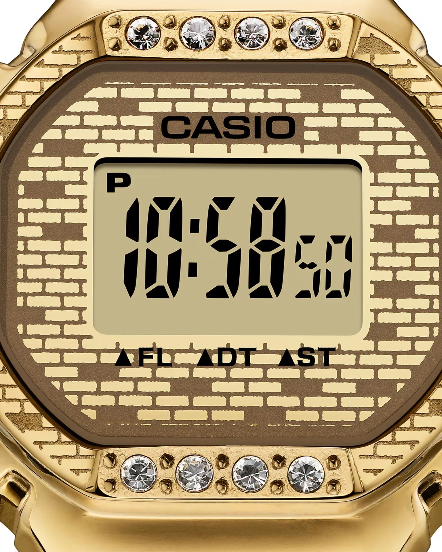Close-up of a gold Casio digital watch face with a brick pattern background and four crystals above and below the display.