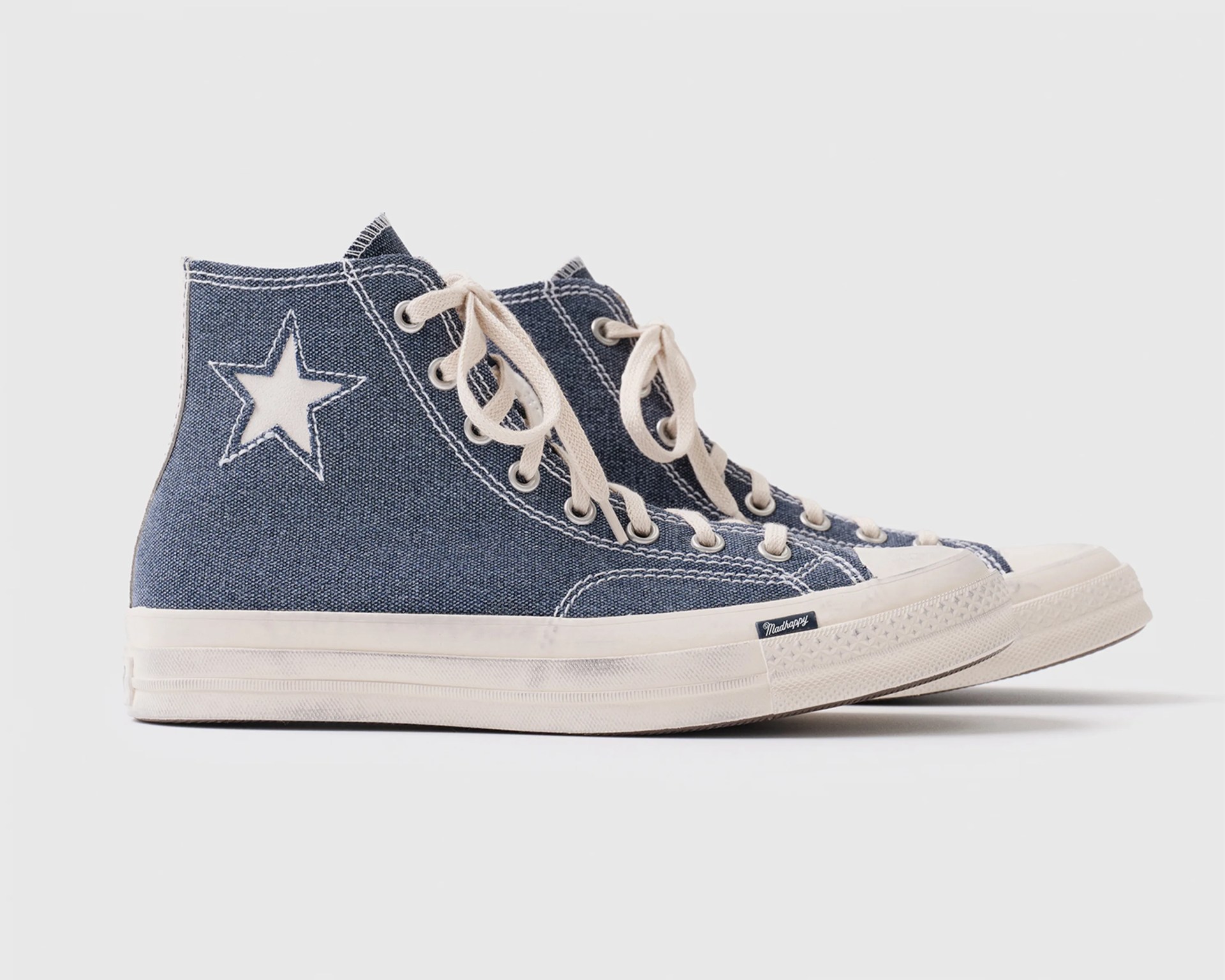 Pair of blue high-top canvas sneakers with white star patch and cream laces on white background.