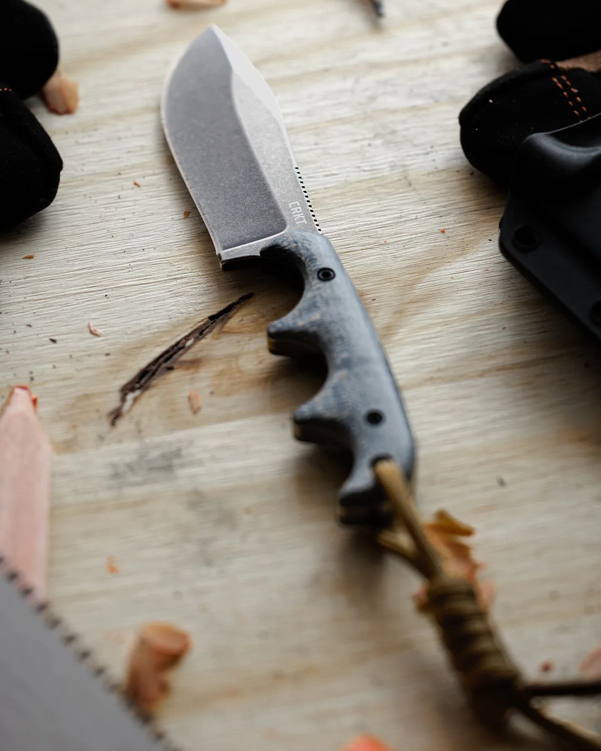 Fixed-blade knife with a stonewashed blade and textured gray handle on a wooden surface.