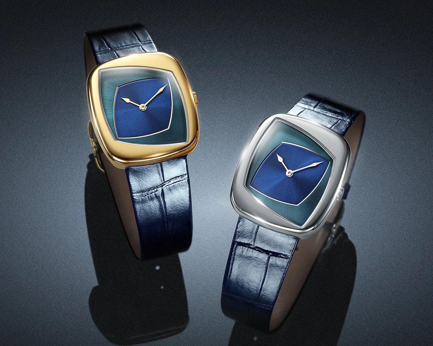 Two wristwatches with blue leather straps, one with a gold case and the other with a silver case, both featuring blue dials.