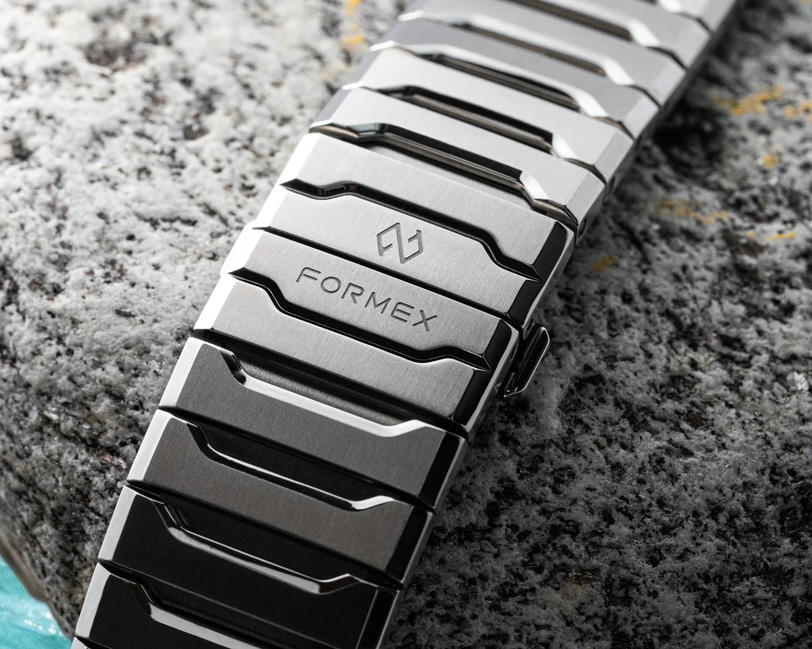 Brushed and polished stainless steel watch bracelet with "FORMEX" engraving on a granite surface.