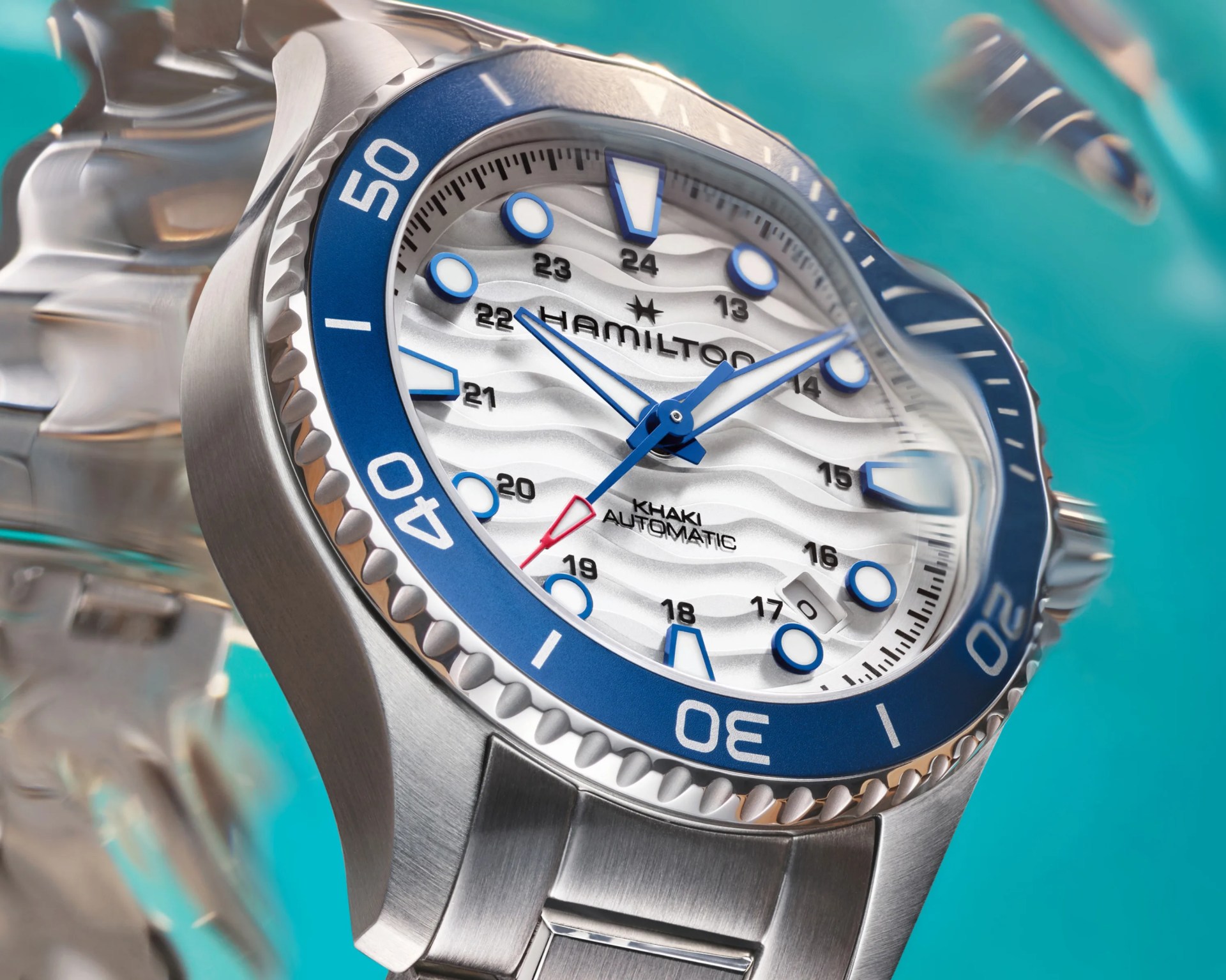 Silver Hamilton Khaki Automatic watch with blue bezel and white dial featuring wave pattern and blue hour markers.