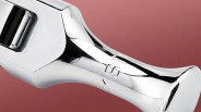 Close-up of a shiny chrome wrench head on a textured reddish-brown background.