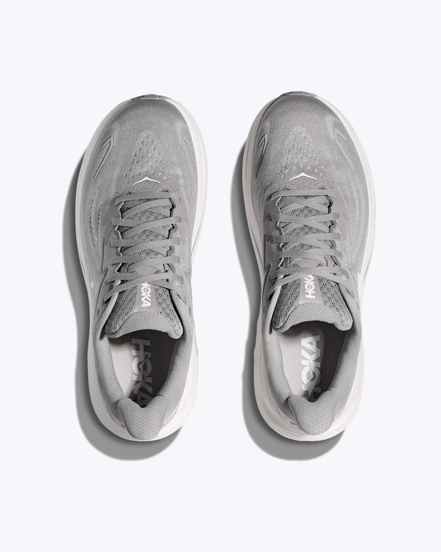 Pair of gray Hoka running shoes with white soles viewed from above on a white background.