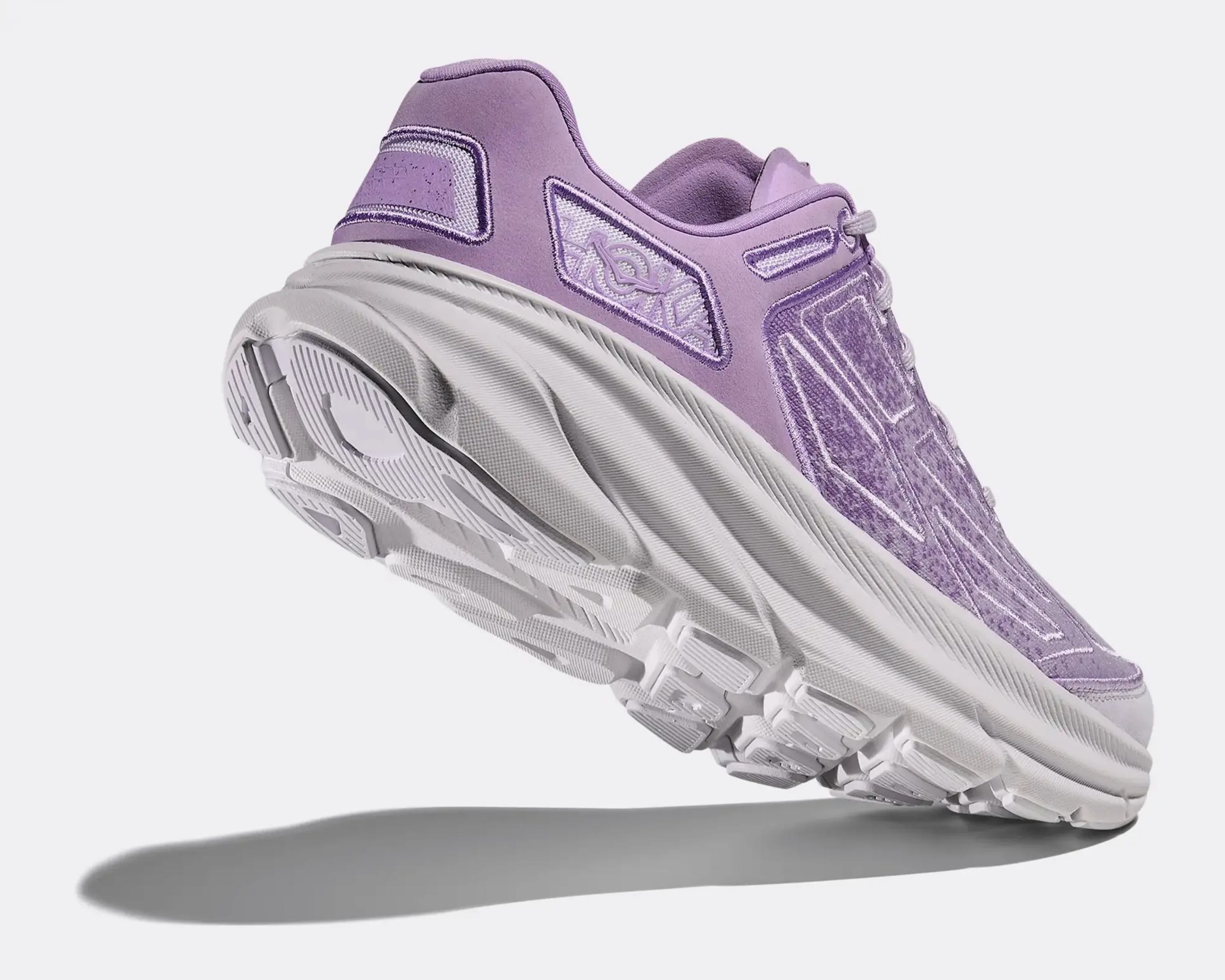 Lavender and white athletic shoe with thick sole and textured outsole, shown from a low rear angle.