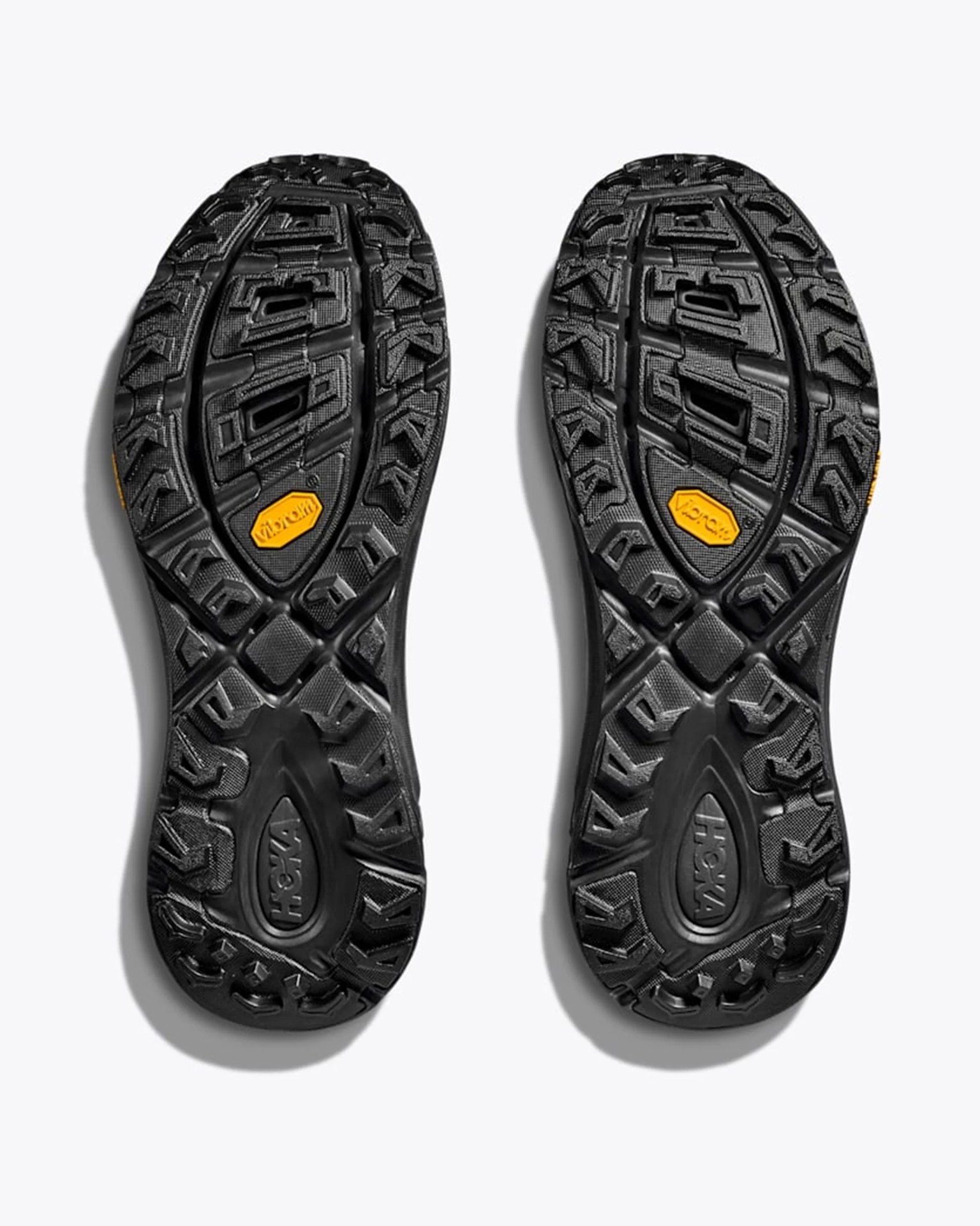 Black rugged shoe soles with deep treads and yellow Vibram logos in the center.