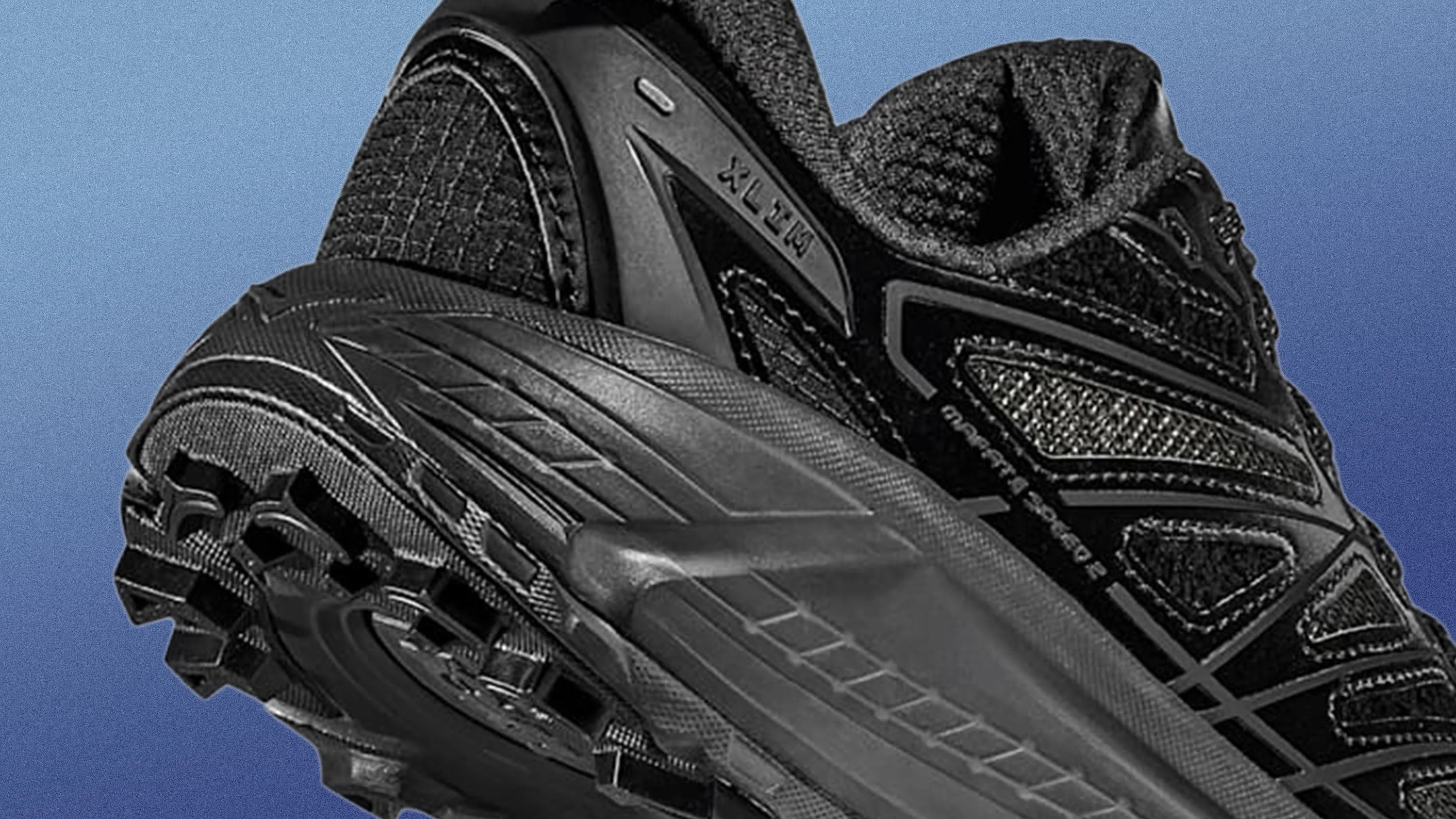 Close-up of a black athletic shoe with textured sole and mesh upper, showing "XL-ITW" and "MADE IN JAPAN" text.