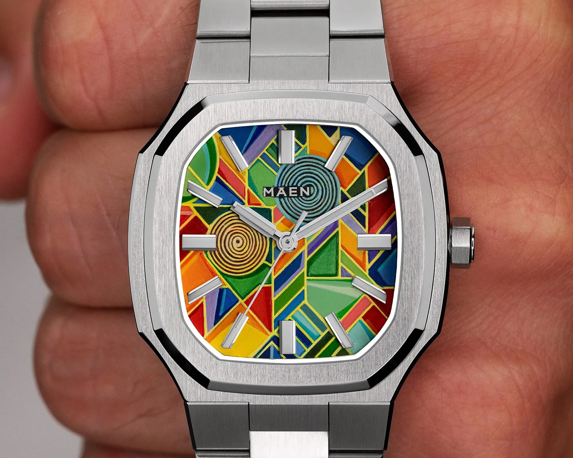 Stainless steel wristwatch with a colorful geometric patterned dial and silver hour markers and hands.
