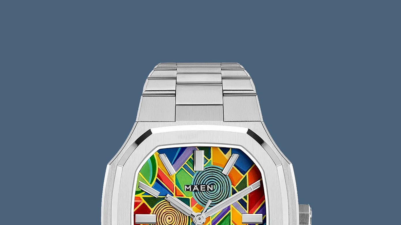 Silver metal wristwatch with a colorful geometric patterned dial and the brand name "MAEN" on the face.