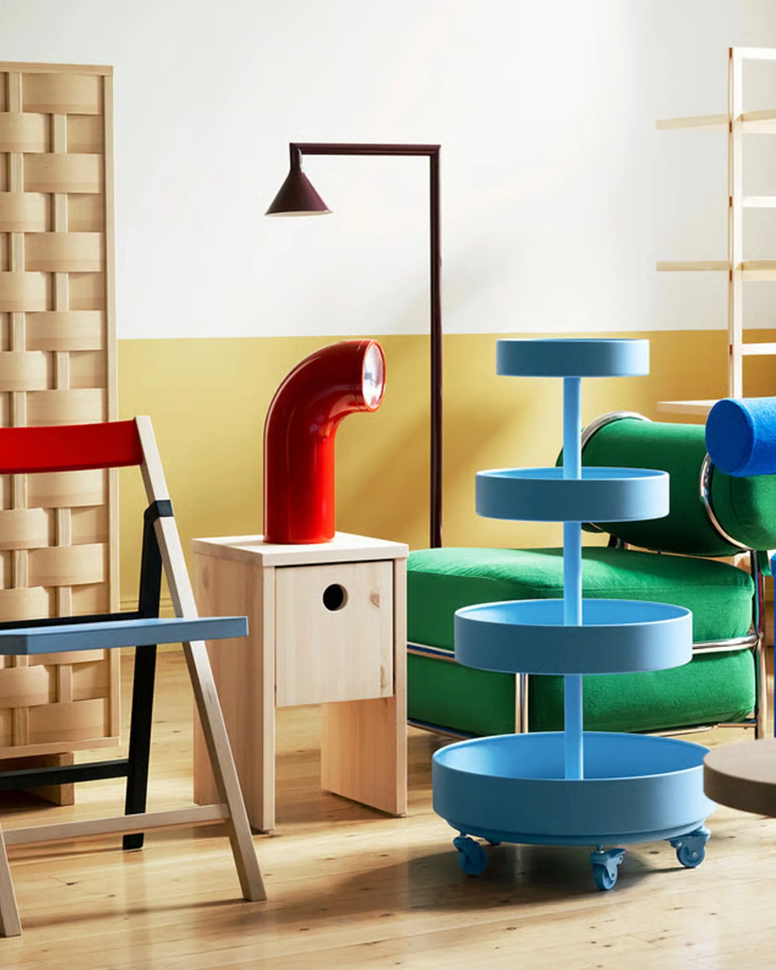 Blue three-tier rolling storage cart next to a green upholstered chair with a cylindrical headrest.