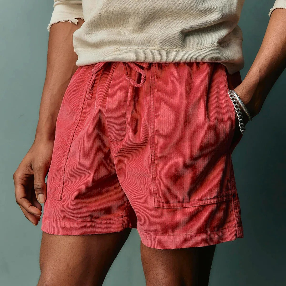 Red corduroy shorts with front patch pockets and a drawstring waist worn by a person.