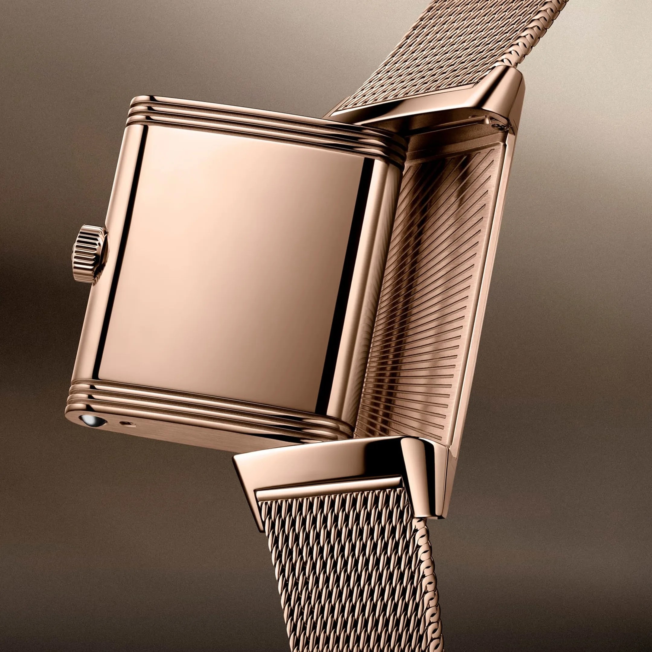 Rose gold rectangular watch case with a textured mesh strap and a crown on the side.