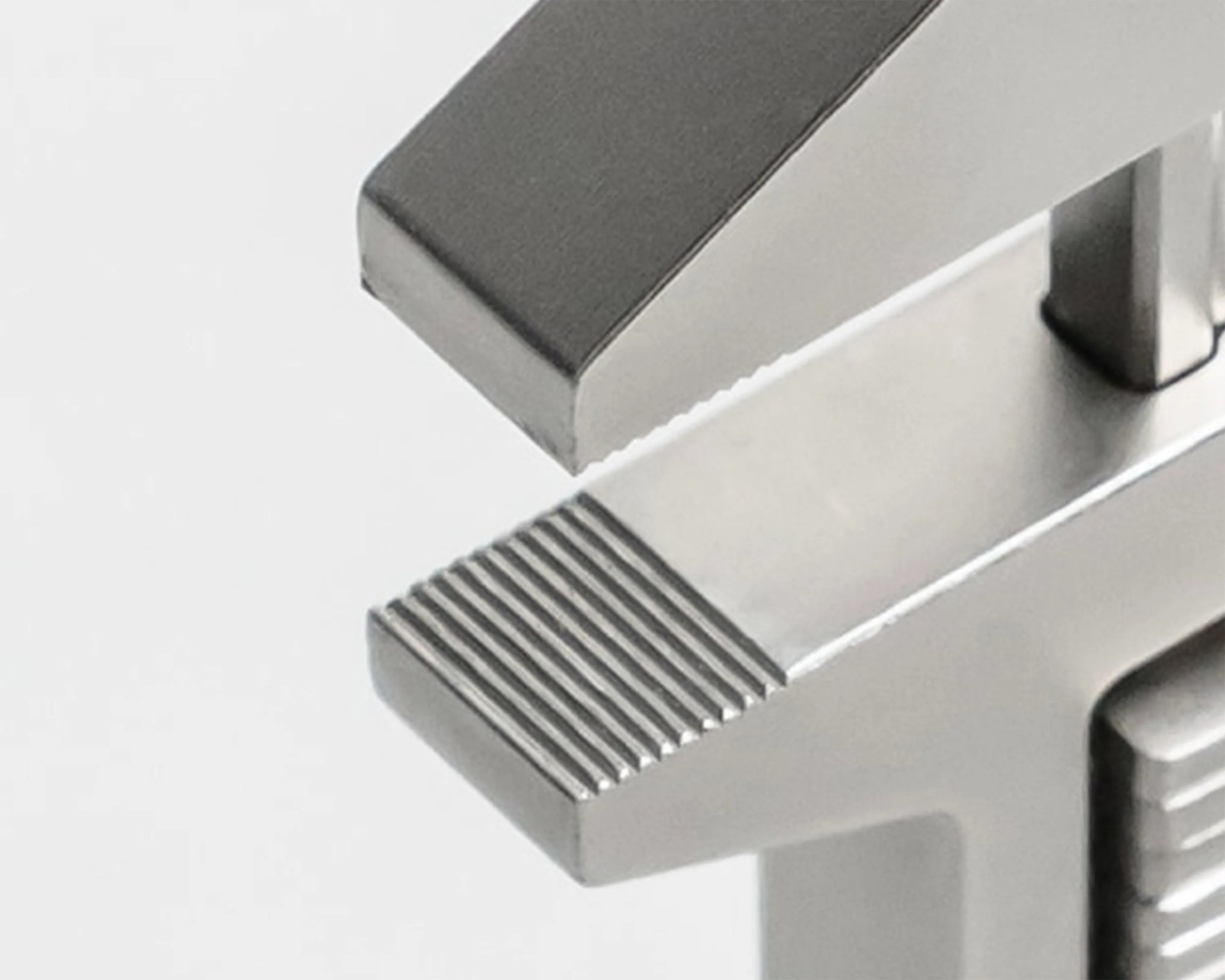Close-up of a metallic object with a textured, grooved surface and a smooth, angled edge.