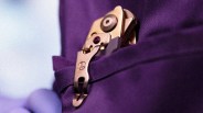 Compact metallic multi-tool clipped to the edge of a purple fabric pocket.