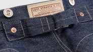Close-up of dark blue denim jeans waistband with Levi Strauss & Co. label and metal buttons.